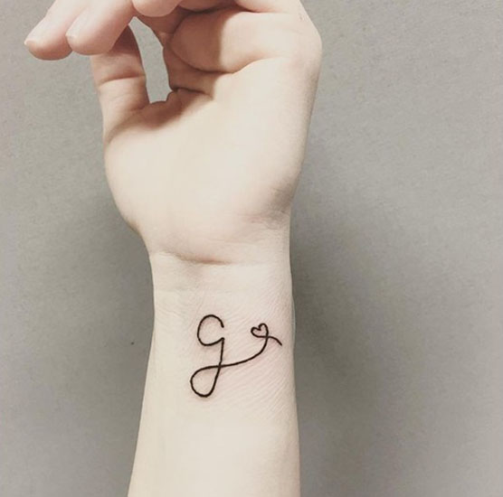 G betű tetoválás szívvel a csuklóján