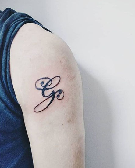 Csavart G betűs tetoválás