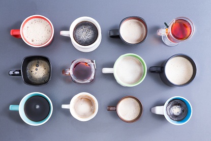 Koncepcionális kép, amely a napi koffeinadag idejét ábrázolja, felülnézetben tizenkét különböző csésze, bögre és pohár, elrendezése forró friss teával és kávéval szürke színben