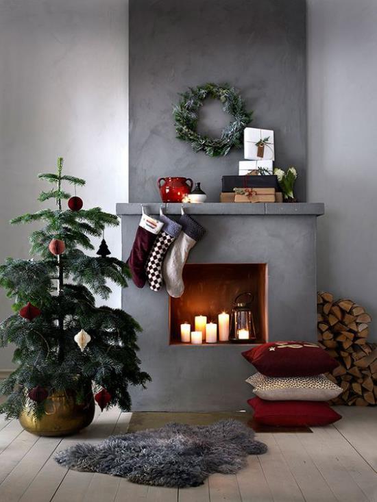 unenomaiset joulukoristeet olohuoneessa pieni joulukuusi takka kynttilät harmaa tausta teollinen tyyli