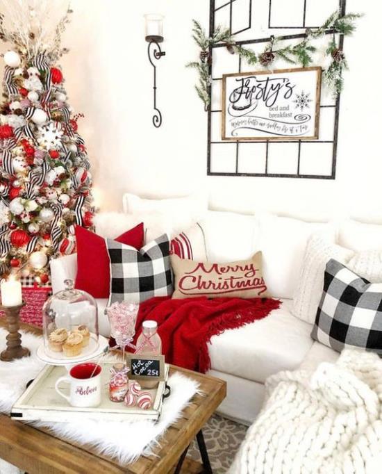unenomaiset joulukoristeet olohuoneessa valkoinen sohva punainen aksentti viihtyisät peitotyynyt kuusen vasemmalle