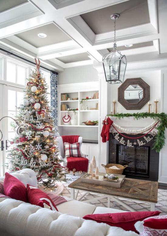 unenomaiset joulukoristeet olohuoneessa valkoiset sohvat punaiset tyynyt kuusipuu vihreä seppele takan ääressä