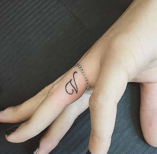 Pompás V betűs tetoválás az ujján