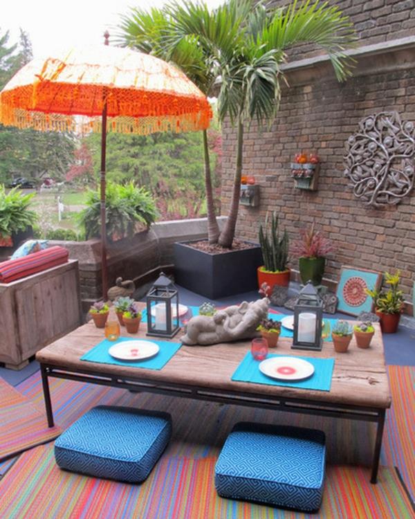 verantajuhla kesällä intialaisen tunnelman patsailla ja aurinkovarjo oranssilla