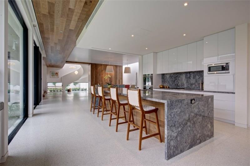 valkoiset keittiökaapit kiiltävä marmorinen keittiösaari keittiö takaseinä graniittilaatat