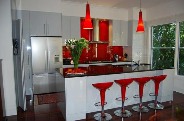 moderni keittiö valkoinen keittiösaari punainen baarituoli riippuvalaisimet