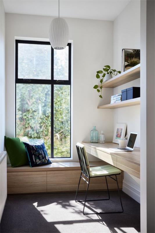 nykyaikainen kotitoimisto yksinkertaisesti mutta mukavasti kalustettu penkki valkoiset tyynyt ikkunapöydässä avoin hylly vaalea puu